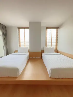 two beds in a room with two windows at Wynora Hotel in Khlong Toei