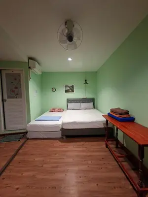 a green bedroom with two beds and a table at Santo house no66 in Bangkok