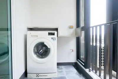 a washing machine in a room with a balcony at 5 mins to BTS Ekkamai, One Bed Fully-Furnished in Bangkok