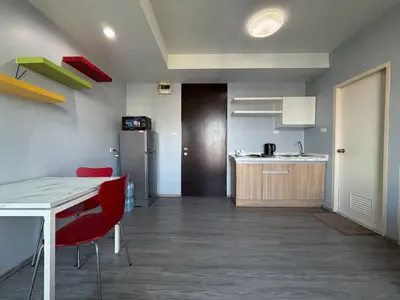 a kitchen with a table and red chairs in a room at Pano Ratchada 19 BKK MRT in Bangkok