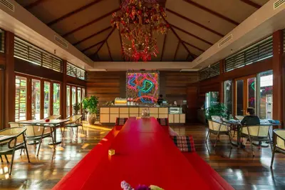 a large red table in a room with tables and chairs at Baan Krai Nao The Riverfront in Bang Chak