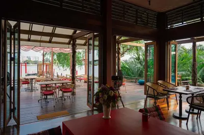 a restaurant with tables and chairs on a deck at Baan Krai Nao The Riverfront in Bang Chak