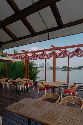 a deck with tables and chairs and a view of the water at Baan Krai Nao The Riverfront in Bang Chak
