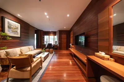 a living room with wooden walls and a couch and chairs at Baan Krai Nao The Riverfront in Bang Chak