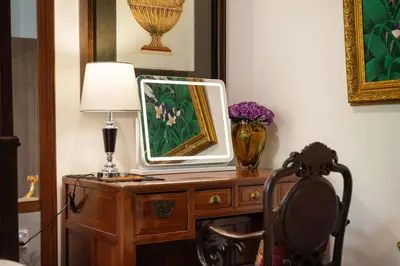 a mirror on a dresser with a lamp and a chair at Star House Classic Style in Bangkok
