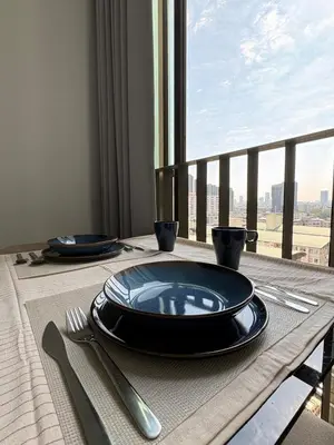 a table with plates and utensils on a table with a window at Ideo Mix Sukhumvit 103, right next to BTS Udomsuk in Phra Khanong