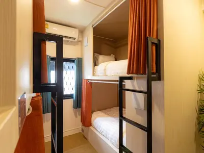 a small room with two bunk beds and a bathroom at Social Pod Khao San Hostel in Bangkok