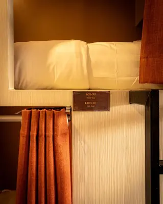 a bunk bed with a mattress and a sign on it at Social Pod Khao San Hostel in Bangkok