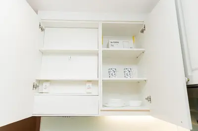 a white pantry with white shelves and dishes at Lux Condo 2BR - 5 mins walk to BTS Phrom Phong in Bangkok