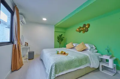 a green bedroom with a bed with a tray of fruit on it at Arta House in Bangkok