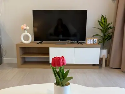 a living room with a tv and a vase with red flowers at Cozy Studio near Train Night market & BKK Airport in Bangna