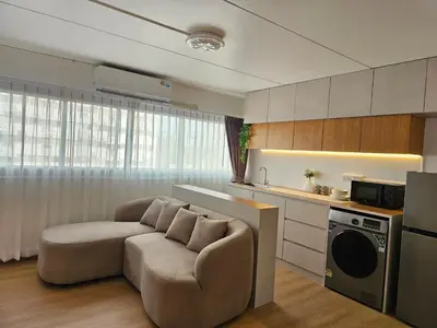 a living room with a couch and a kitchen at Jumboboom in Ban Bang Phang