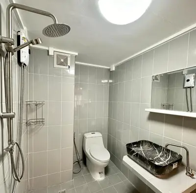 a white bathroom with a toilet and a shower at Jumboboom in Ban Bang Phang