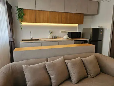 a living room with a couch in front of a kitchen at Jumboboom in Ban Bang Phang