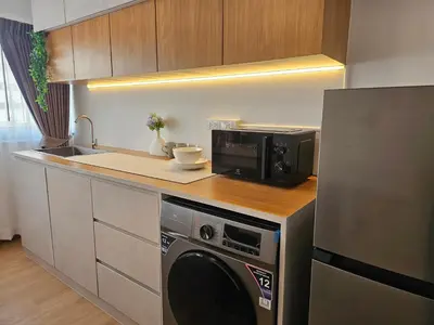 a kitchen with a washing machine and a microwave at Jumboboom in Ban Bang Phang