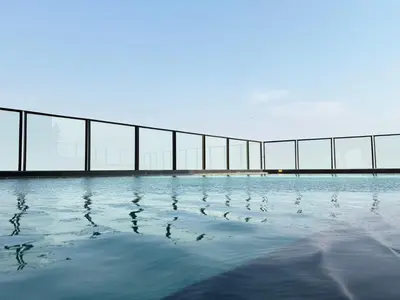 a pool of water with a bridge in the background at Bangkok Rama9 Cassia & Siamese in Bangkok
