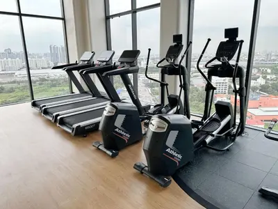 a row of treadmills in a gym with windows at Bangkok Rama9 Cassia & Siamese in Bangkok