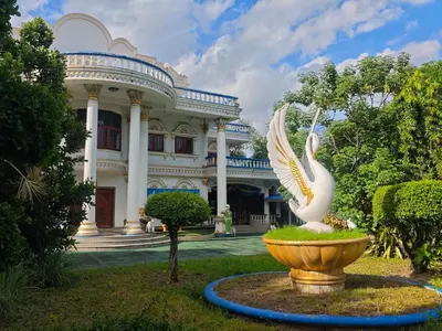 a large white building with a statue in front of it at Worsakornrit Homestay in Bangkok