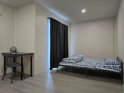 a room with a bed and a table in it at Baan White House in Ban Baen Phichit