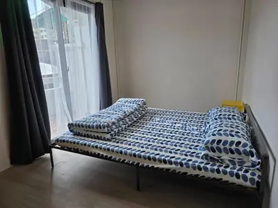 an empty bed in a room with a window at Baan White House in Ban Baen Phichit