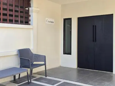 a bench and a chair in front of a door at Baan White House in Ban Baen Phichit