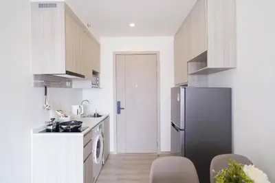 a kitchen with a refrigerator and a table and chairs at The Hampton Suites Bangna in Bangna