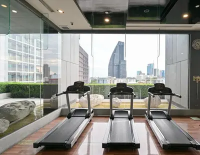 a gym with three treadmills in front of a large window at Thonglor BTS Prime Pool gym Netflix city in Bangkok