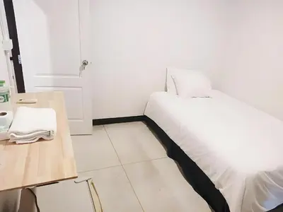 a white bedroom with a bed and a table at GO INN Asiatique - Riverfront Bang Kho Laem