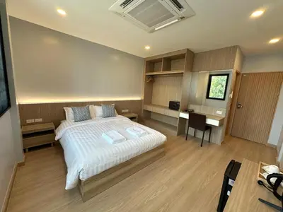 a bedroom with a bed and a desk in it at Whiteinn - ไวท์อินน์ in Nonthaburi
