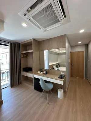 a room with a desk and a bed with a mirror at Whiteinn - ไวท์อินน์ in Nonthaburi