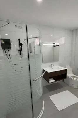 a bathroom with a shower and a sink and a toilet at Whiteinn - ไวท์อินน์ in Nonthaburi
