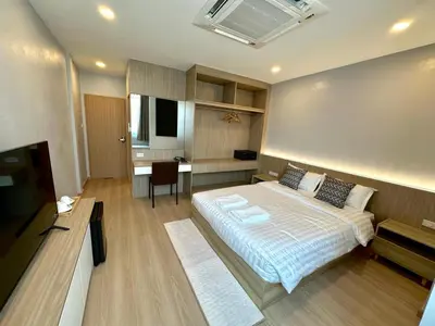 a bedroom with a bed and a desk and a television at Whiteinn - ไวท์อินน์ in Nonthaburi