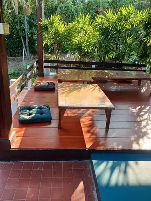 a wooden deck with a bench and some plants at Chan Klong No8 Homestay - บ้านชานคลองหมายเลข8 in Sathani Wat Sing