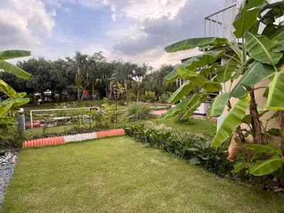 a garden with green grass and trees in the background at Chan Klong No8 Homestay - บ้านชานคลองหมายเลข8 in Sathani Wat Sing