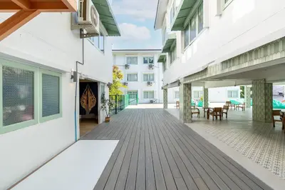 an empty courtyard of a building with a wooden deck at Capsule Hostel and Thai Traditional Bath Bangkok in Bangkok
