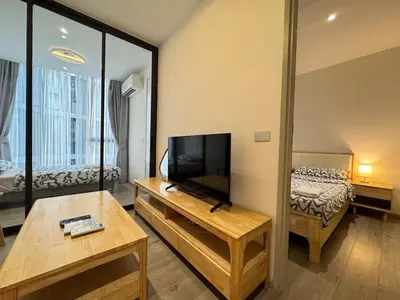 a living room with a television and a bedroom at Fynn Bangkok Asoke Condo in Bangkok