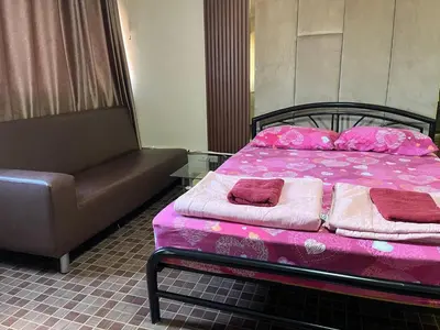 a bed with pink sheets and a couch in a room at Impact Arena C4 by Jintana in Ban Bang Phang