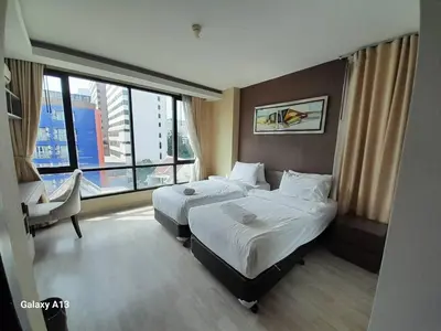 a hotel room with two beds and a window at Avatar Suites Hotel - SHA Extra Plus in Bangkok