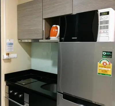 a microwave on top of a refrigerator in a kitchen at Avatar Suites Hotel - SHA Extra Plus in Bangkok
