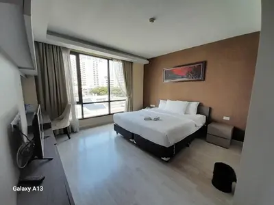 a hotel room with a bed and a television at Avatar Suites Hotel - SHA Extra Plus in Bangkok
