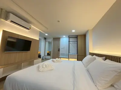 a bedroom with a large white bed with a flat screen tv at Armass Residence in Bangna