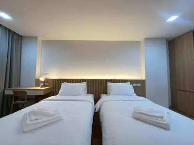 two beds in a hotel room with towels on them at Armass Residence in Bangna
