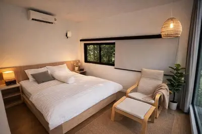 a bedroom with a bed and a chair and a window at Feel Private Pool Villa in Ban Lam Praya Phai Rua