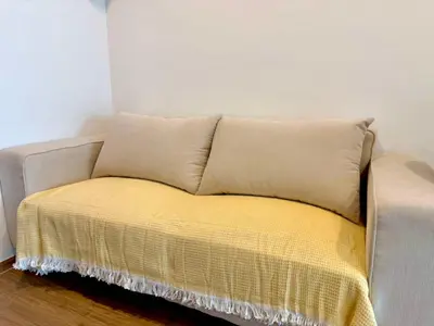 a couch with a yellow blanket on top of it at Bangkok Condo Ramkhamhaeng in Sathani Ban Hua Mak