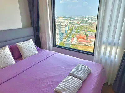 a bedroom with a purple bed and a large window at Bangkok Condo Ramkhamhaeng in Sathani Ban Hua Mak
