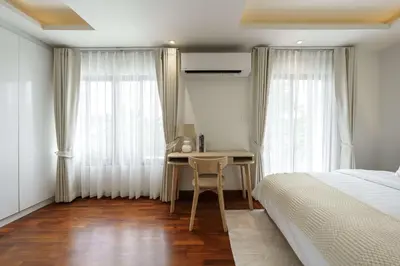 a bedroom with a desk and a bed and curtains at Bhumidol Home near Don Muang Airport in Lak Si