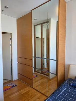 a bedroom with a large wooden closet with glass shelves at Chaophraya River high-rise river view apartment direct access to iconsiam Siam Square Chinatown 0 distance from BTS subway exit direct to Sathorn Silom Road Siam Square in Bangkok