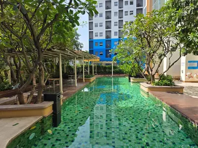 a swimming pool with green water and trees and a building at Chaophraya River high-rise river view apartment direct access to iconsiam Siam Square Chinatown 0 distance from BTS subway exit direct to Sathorn Silom Road Siam Square in Bangkok
