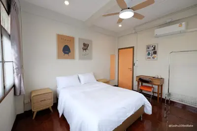 a bedroom with a white bed and a desk at Sadhu10BedBake in Bangkok