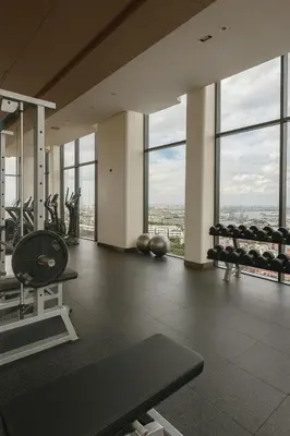 a gym with cardio equipment in a building with windows at High-Ceiling Loft Suite Rama 9 Design Apartment in Bangkok